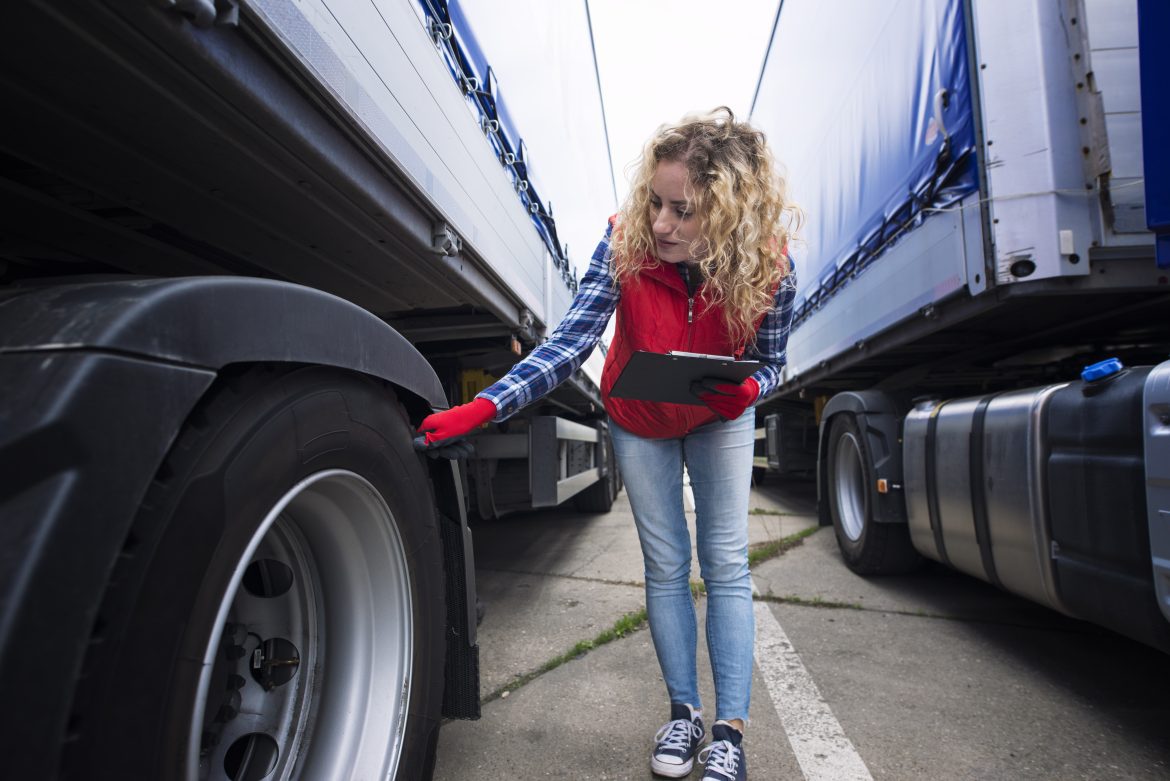Truck driver checking vehicle tires and inspecting truck before ride.